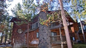 A rustic cabin with a stone chimney, wooden siding, and a balcony. - Cozy Sunriver Golf Condo with Access to Exclusive Golf (Sunriver)