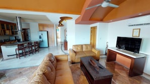 A spacious living area with a sofa, TV, and a dining area with chairs and a table.