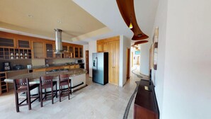 A modern kitchen with a central island, wooden cabinets, and a stainless steel refrigerator. - Andales on the Bay Suites (Puerto Vallarta)
