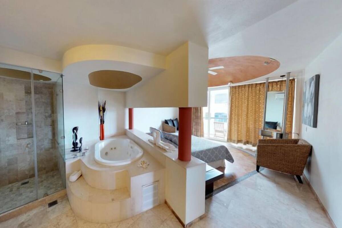 Ein modernes Badezimmer mit einer gläsernen Duschkabine, einer freistehenden Badewanne und einer Sitzecke mit Sofa und Korbsessel.