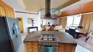 A kitchen with a gas stove, wooden cabinets, and a modern pendant light. - Andales on the Bay Suites (Puerto Vallarta)