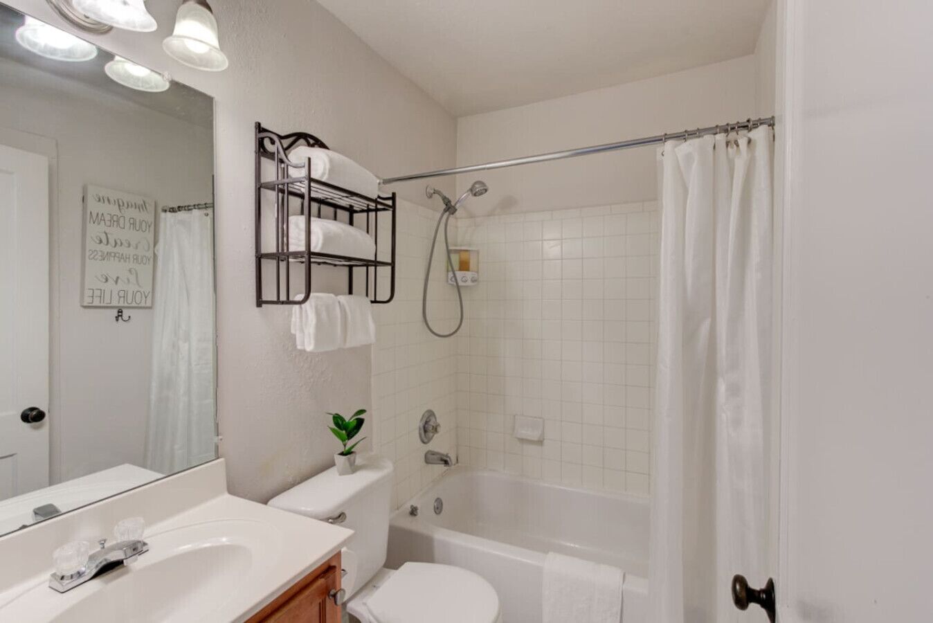 A bathroom with a bathtub, toilet, sink, and a towel rack with towels.