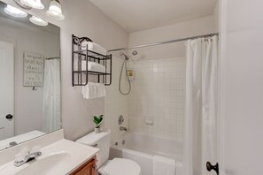 A bathroom with a bathtub, toilet, sink, and a towel rack with towels.