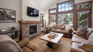 Una sala de estar acogedora con chimenea de piedra, ventanas amplias y asientos cómodos.