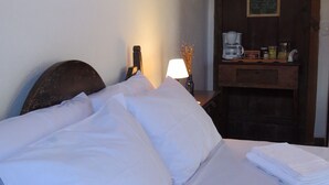 A neatly made bed with white linens, a bedside lamp, and a small table with a coffee maker and other items. - Vila Santíssima - high point of the Historic Center (Tiradentes)