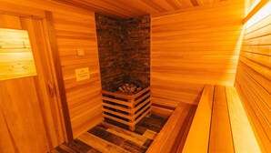 Una sala de sauna con paredes de madera y una chimenea de piedra en el centro.