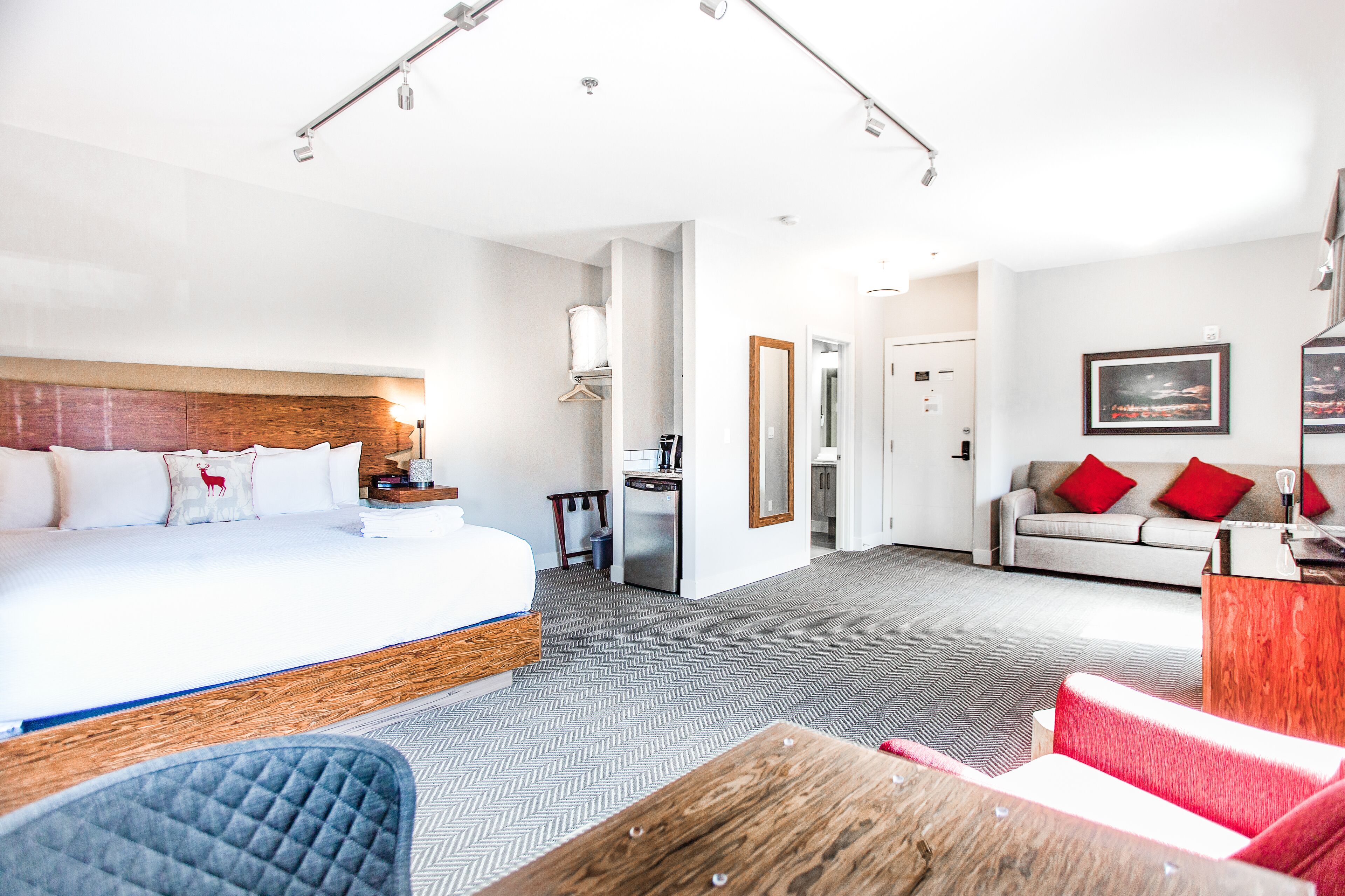 A hotel room with a large bed, a desk, a sofa, and a dining table.