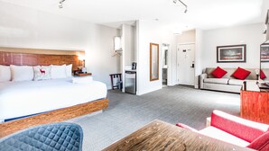 Habitación de hotel con una cama grande, un escritorio, un sofá y una mesa de comedor.