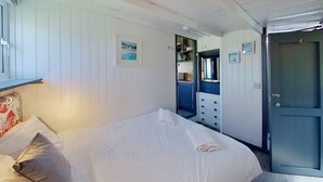 A room with a bed, a dresser, a mirror, and a door. - E19 Roskear, Riviere Towans (Hayle)