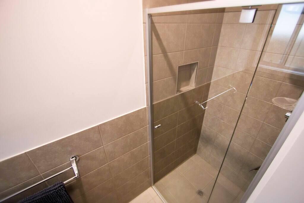 Un petit espace douche fermé, doté d’une porte en verre, d’un porte-serviettes et de toilettes.