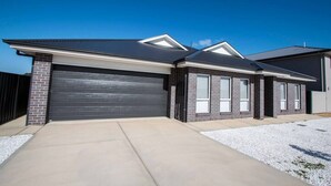 A modern two-story house with a dark garage door, a brick exterior, and a clear sky.
