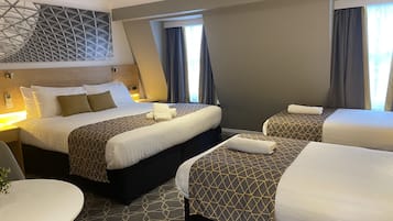 A hotel room with two beds, a round table, and a modern ceiling design.