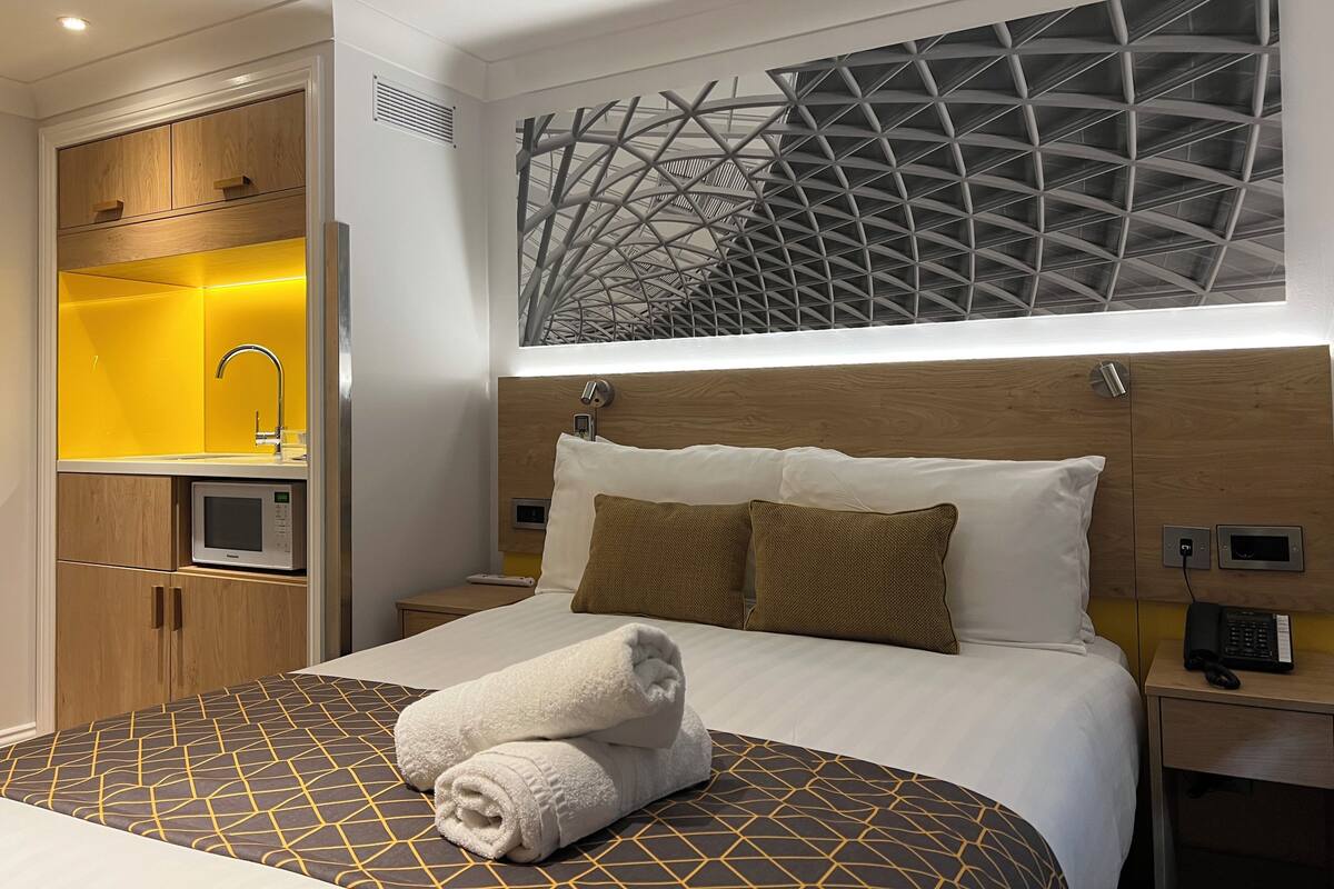 Una camera d'albergo con un letto, un forno a microonde integrato, un lavandino e un soffitto decorato.
