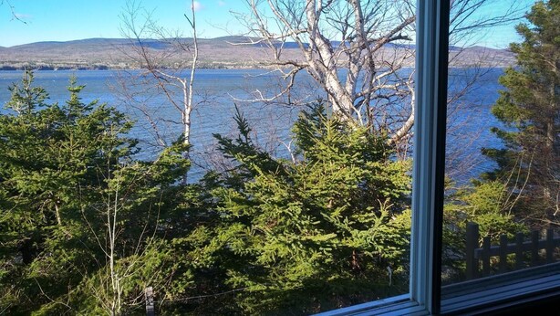 A view of a lake with trees in the foreground and mountains in the background. - Motel Fort Ramsay (Gaspe)