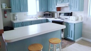 A kitchen with blue cabinets, a white island, and two stools. - Motel Fort Ramsay (Gaspe)