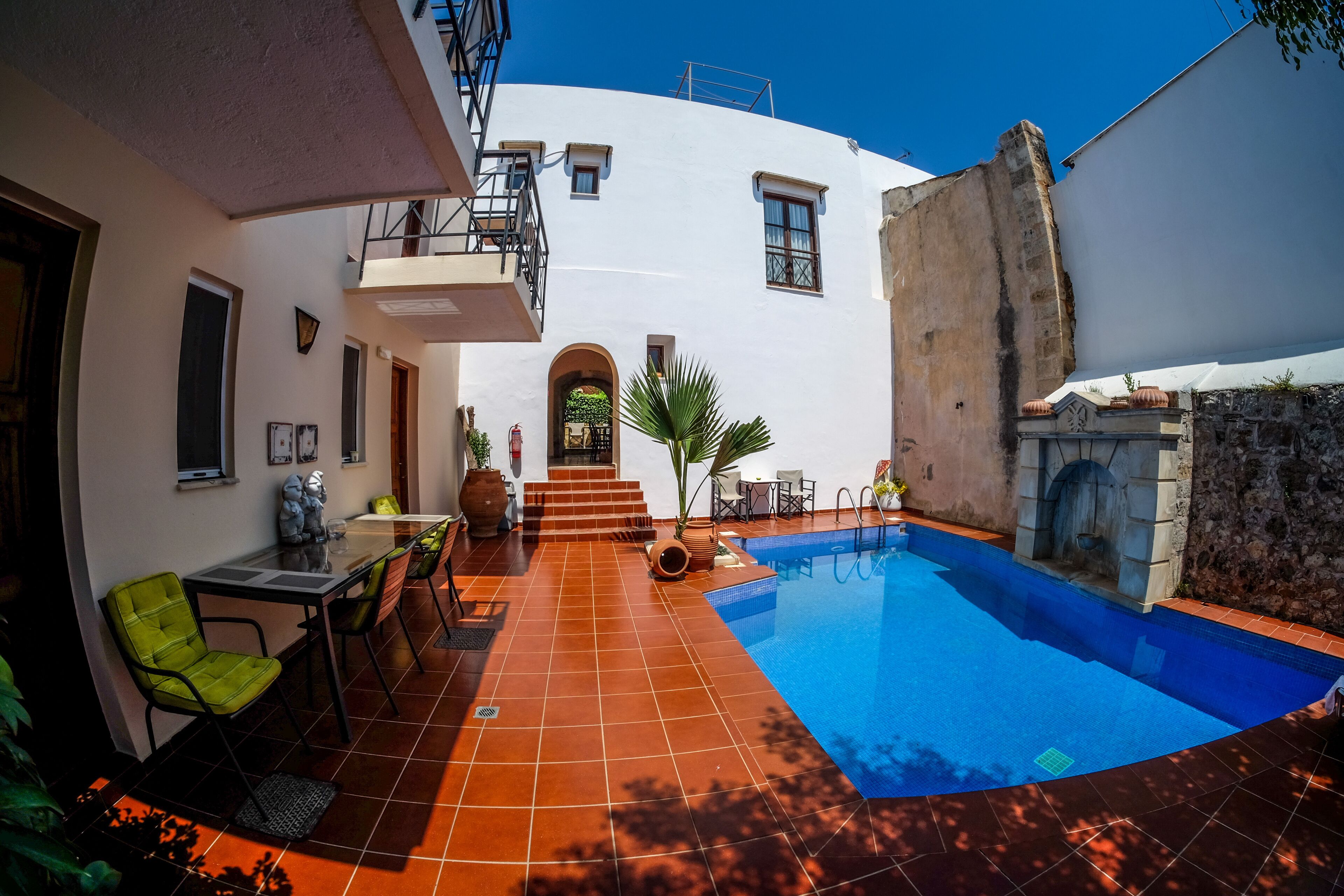 A courtyard with a swimming pool, outdoor seating, and a staircase leading to a covered area.
