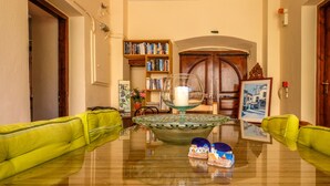 Een woonkamer met een glazen salontafel, een boekenkast en een deur met een decoratieve knop.