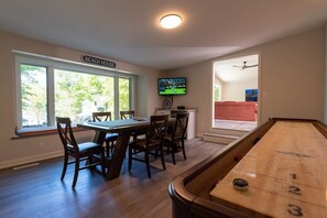 A room with a pool table, a dining table with chairs, a television, and a sign reading 'BEACH HOUSE'. - Beach View Cottage - Beautiful View of the Lake! (Holland)