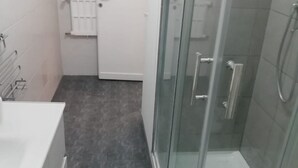 Un bagno con box doccia in vetro, una vasca da bagno bianca e un porta asciugamani.