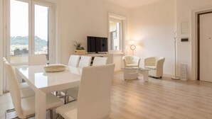 Un soggiorno moderno con angolo da pranzo, TV a schermo piatto e vista sull'esterno.
