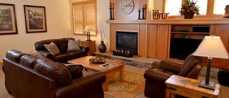 A living room with a fireplace, leather sofas, a coffee table, and a television.