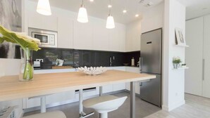 Cucina moderna con isola centrale, luci a sospensione ed elettrodomestici in acciaio inossidabile.
