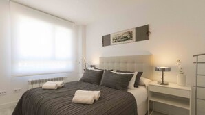 Una camera da letto ordinata con un letto grande, un comodino con una lampada e un termosifone sotto la finestra.