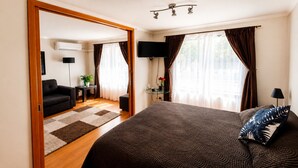 Un dormitorio con cama, televisor, escritorio, silla y sofá.