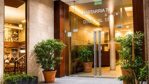 Entrada de un hotel con un cartel que dice 'LASTARRIA 70 DTOS 1 AL 13', plantas en macetas y una puerta de vidrio.