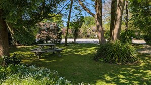 A picnic table in a lush garden with trees and flowers. - 01 Tudor Court, Tolroy Manor (Hayle)
