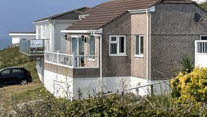 Ein zweistöckiges Haus mit Balkon, ein geparktes Auto davor und Blick aufs Meer.