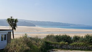 Blick auf die Küste mit Strand, einer Palme und einer Steinmauer.