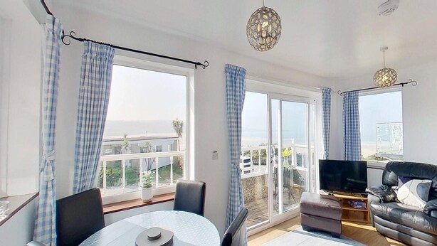 Ein modernes Wohnzimmer mit Balkon, Essbereich und Fernseher.