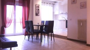 Un comedor con mesa y sillas, un sofá y una cocina al fondo.