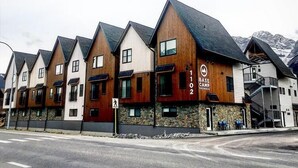 A row of modern cabins with a stone foundation, numbered 1102, and a ski lift visible in the background. - Basecamp Resorts Canmore I Micro-Suite, Dog Friendly (Canmore)