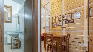 Una habitación con pared de madera, una mesa de comedor con sillas, un estante de madera y un espejo.