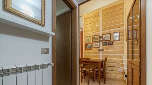 Una habitación con pared de madera, una mesa de comedor con sillas, un radiador y una puerta.