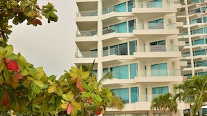 A modern hotel with a large swimming pool surrounded by palm trees and greenery. - APARTAMENTO AMPLIO 3 ALCOBAS FRENTE PLAY (Cartagena)