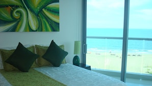 A hotel room with a large bed, a view of the beach, and a painting on the wall. - APARTAMENTO AMPLIO 3 ALCOBAS FRENTE PLAY (Cartagena)