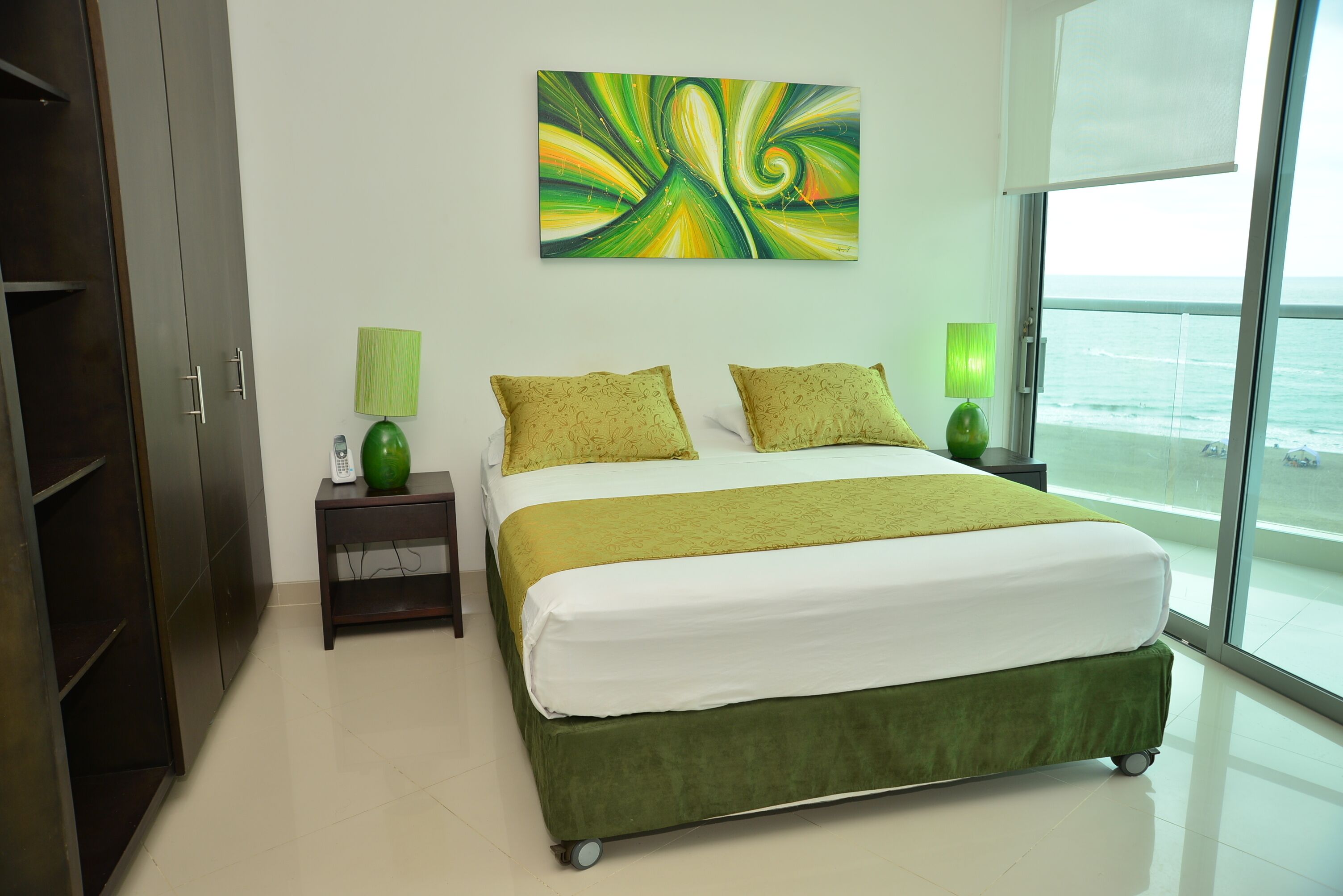 A modern bedroom with a bed, green bedding, two bedside lamps, a green vase, and a large abstract painting on the wall.