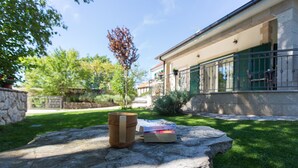 A stone table with a wooden mug and a book in a sunny outdoor setting.