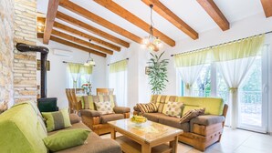 A cozy living room with wooden beams, a fireplace, and a dining area with a table and chairs.