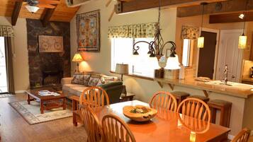 A cozy living room with a fireplace, wooden furniture, and a dining area with a table and chairs.