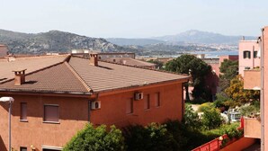 A red brick building with a tiled roof, surrounded by greenery and a view of distant hills. - B&B treatment in La Maddalena, Sardinia (La Maddalena)