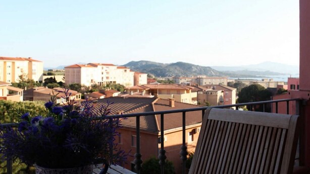 A balcony with a view of a residential area, including buildings and mountains in the distance. - B&B treatment in La Maddalena, Sardinia (La Maddalena)