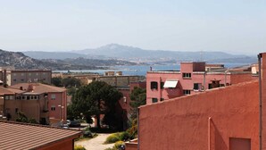 A coastal residential area with buildings, a clear view of the sea, and distant mountains. - B&B treatment in La Maddalena, Sardinia (La Maddalena)