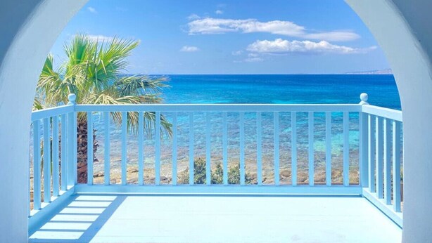 A balcony with a view of a beach and ocean. - Casa Del Mare - Unique Beachfront Cycladic Villa @ Agios Prokopios (Agios Prokopios)