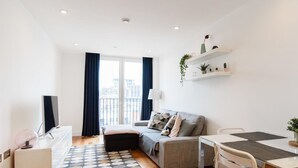 Um apartamento moderno com sofá, mesa de jantar e televisão.