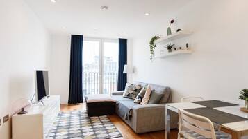 Un apartamento moderno con sofá, mesa de comedor y televisor.