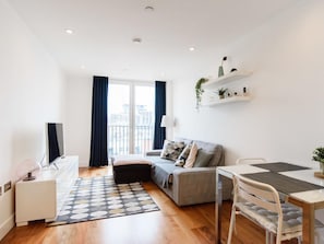 A modern apartment with a sofa, a dining table, and a TV.